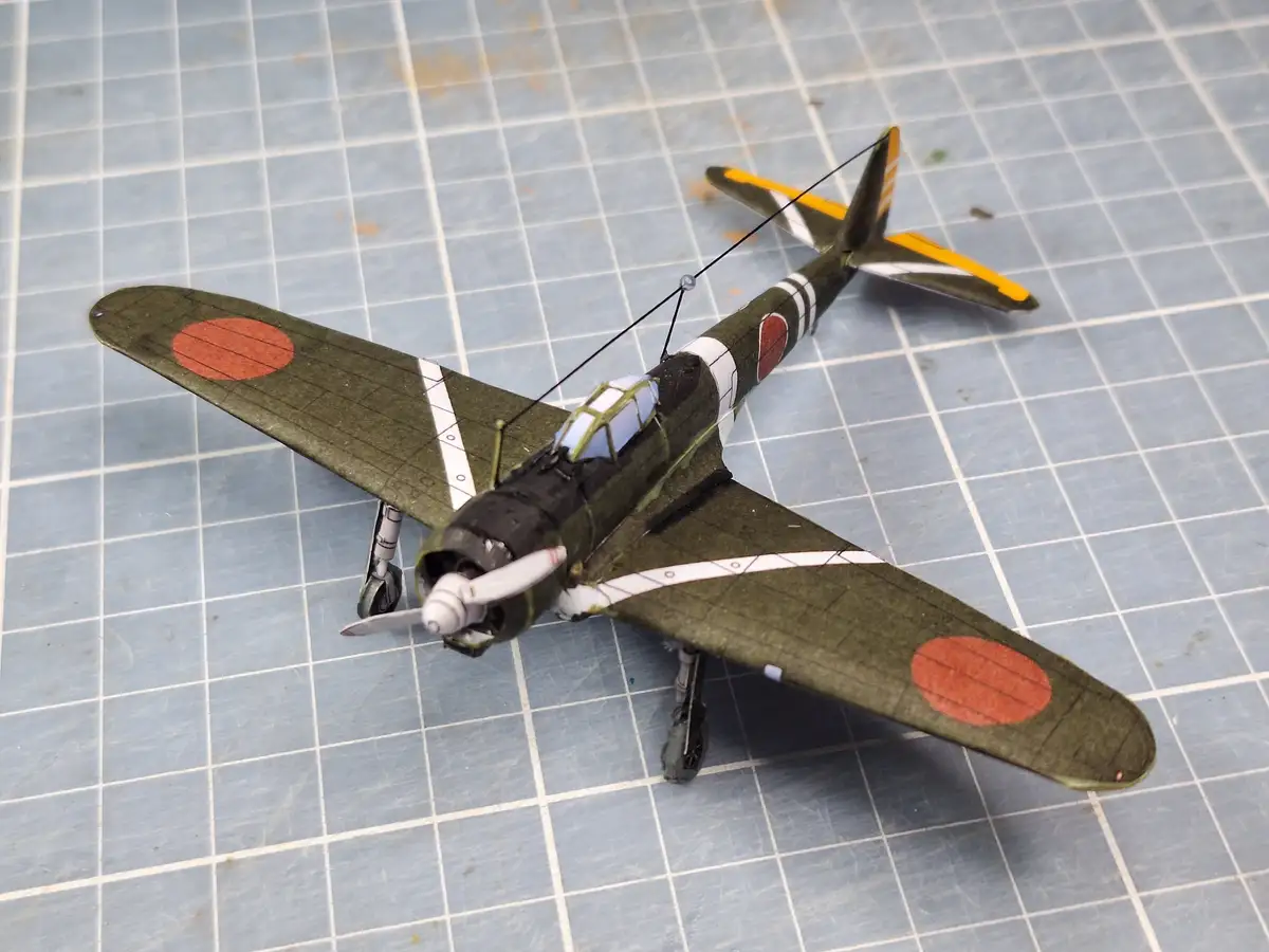 A detailed model of a Japanese World War II fighter plane, likely a Nakadžima Sakae-powered aircraft, sits on a blue…