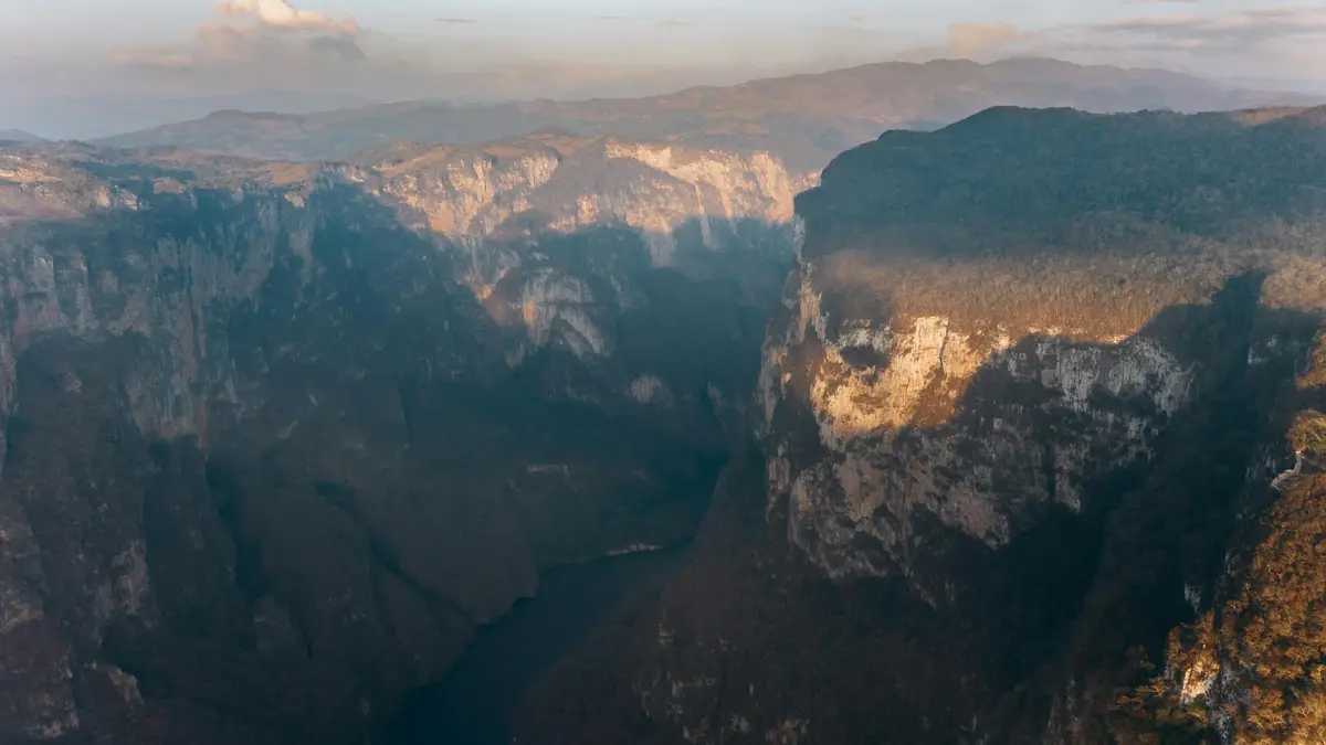 A majestic expanse of rust-hued rock stretches out like a behemoth, its labyrinthine contours etched in golden light…