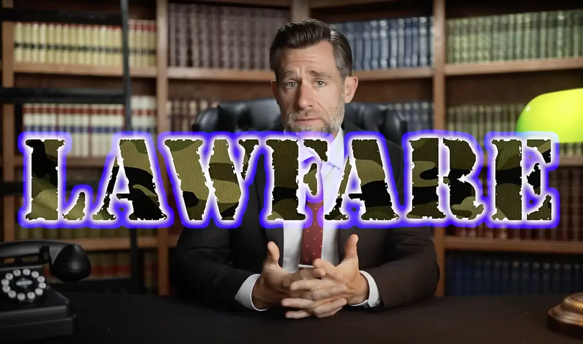 A man in a suit sits at a desk in a law office with bookshelves behind him, looking serious. Large text reading 'LAWFARE' in…
