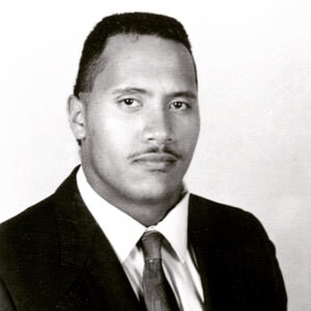 A black-and-white portrait of a young man with short dark hair and a mustache, wearing a dark suit, white collared shirt…