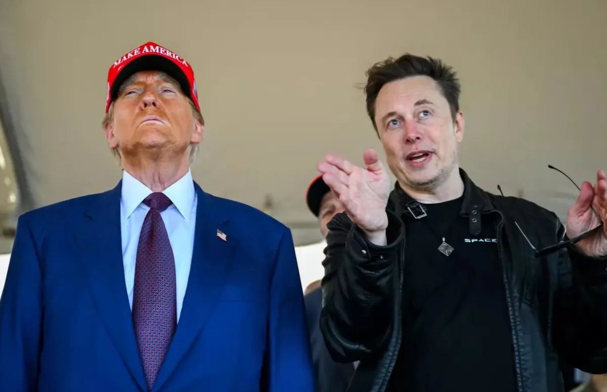 A photo shows Donald Trump wearing a red 'MAKE AMERICA GREAT AGAIN' cap, looking upward with a serious expression, standing…