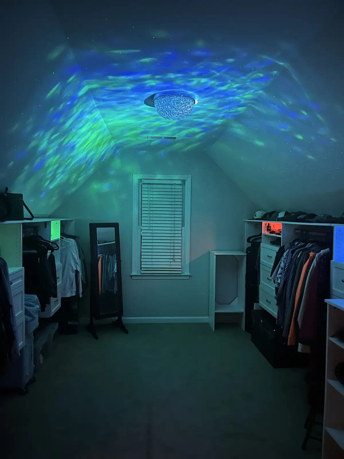 A dimly lit bedroom closet with clothes racks, a mirror, and a window, illuminated by a ceiling projector casting a vibrant…