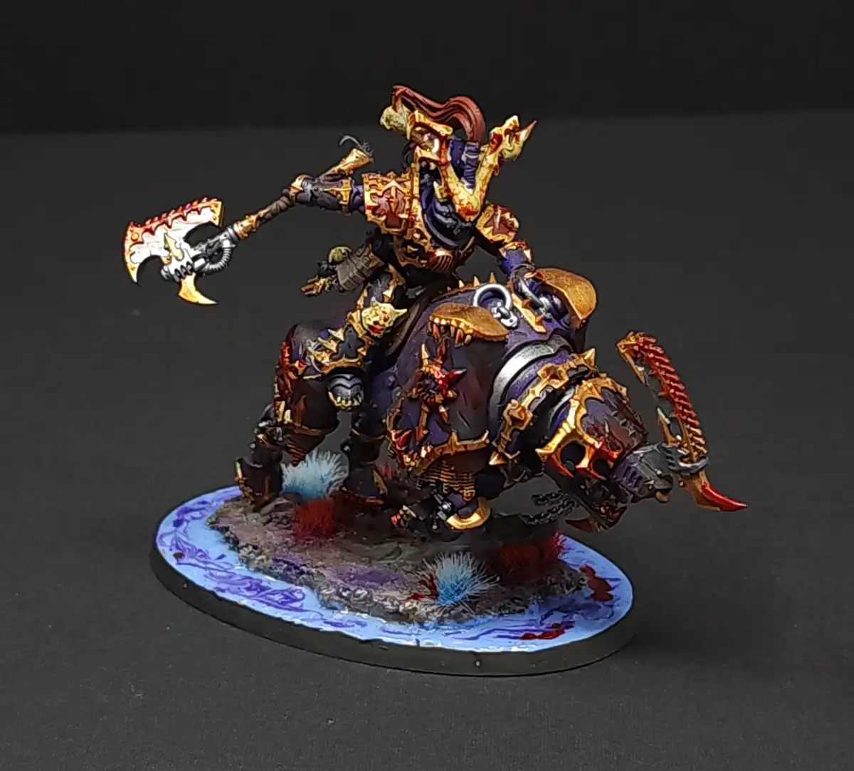 A highly detailed, painted miniature of a fantasy warrior on a monstrous mount, both adorned in ornate purple and gold armor…