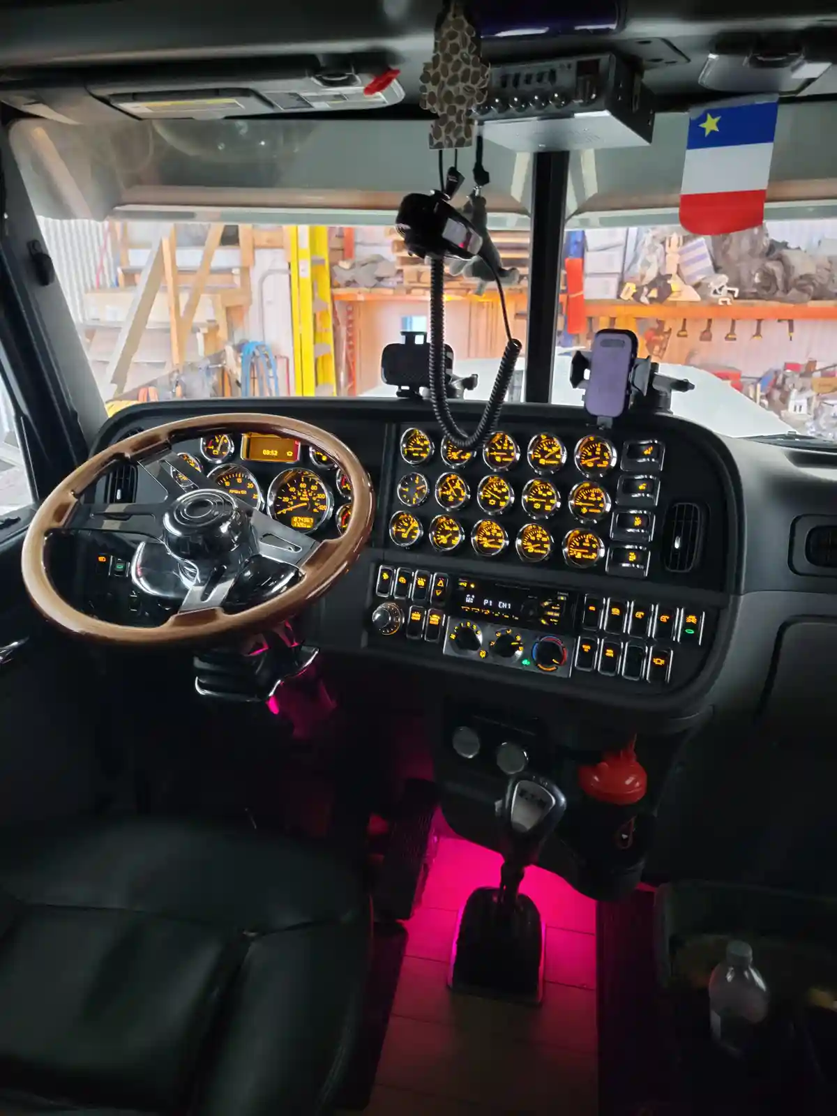 The image shows the interior of a truck cab with a wooden steering wheel, numerous illuminated gauges, and a complex control…
