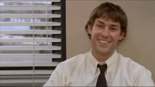 A six-panel meme strip showing actor John Krasinski in an office cubicle, transitioning from a cheerful smile to an excited…