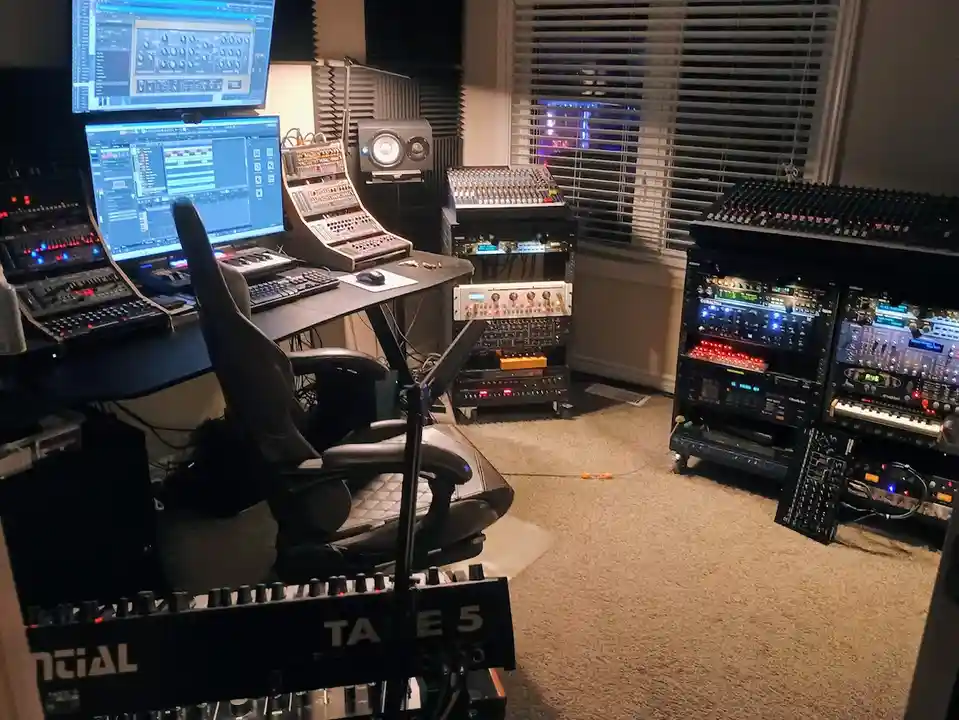 A professional music studio filled with multiple computer monitors, mixing consoles, synthesizers, and audio equipment, with…