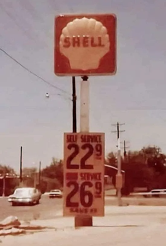 A vintage photo of a Shell gas station sign showing prices: 'SELF SERVICE 22 9' and 'FULL SERVICE 26 9'. The image has a…