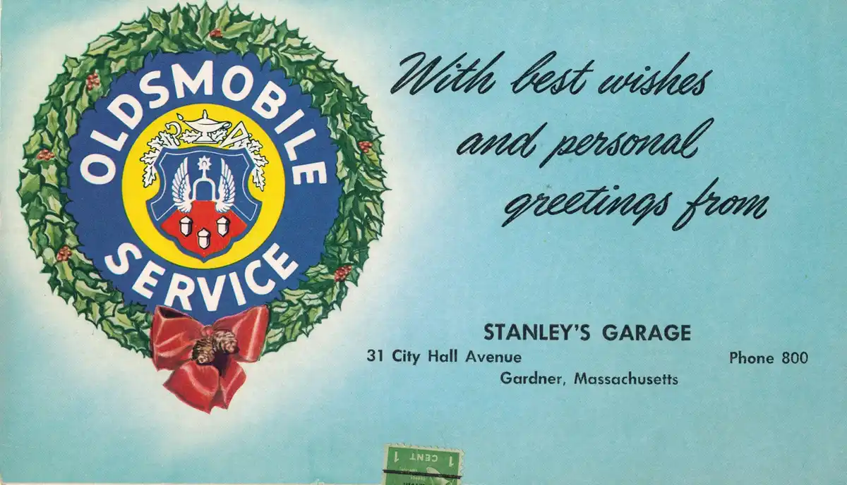A vintage Oldsmobile Service holiday greeting card features a festive holly wreath with a red bow surrounding the Oldsmobile…