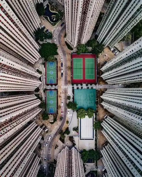 An aerial view looking straight down into a dense urban area surrounded by tall apartment buildings. In the center, several…