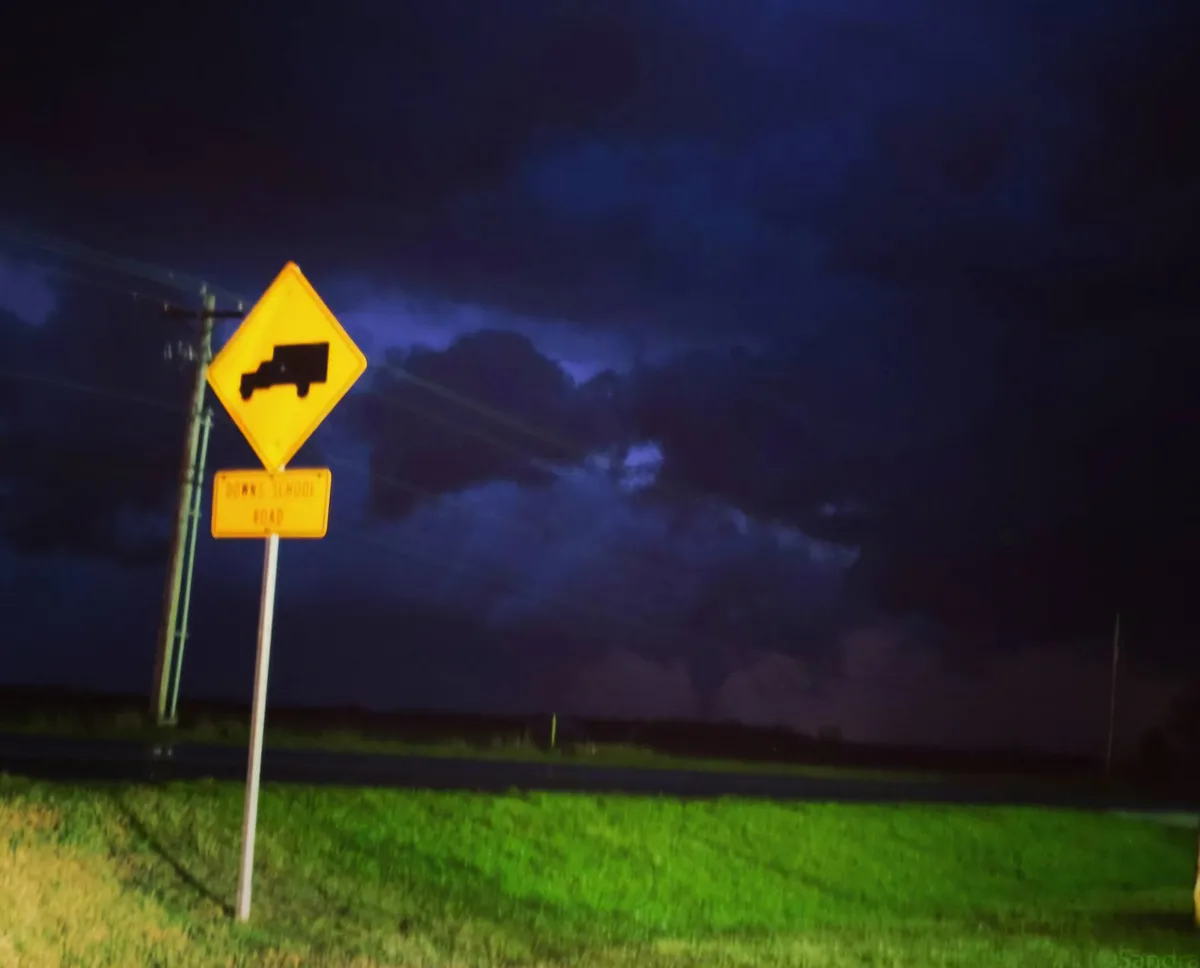 A yellow diamond-shaped road sign with a black truck silhouette is mounted above a rectangular yellow sign that reads 'downs…