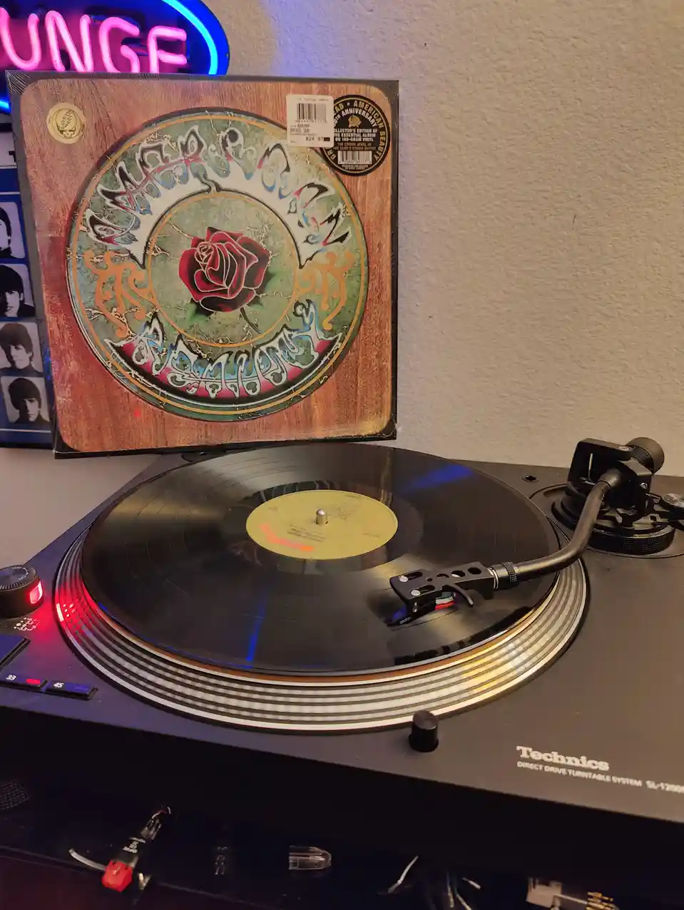 A Technics SL-1200 turntable plays a vinyl record, with the album cover for Grateful Dead's 'American Beauty' standing…