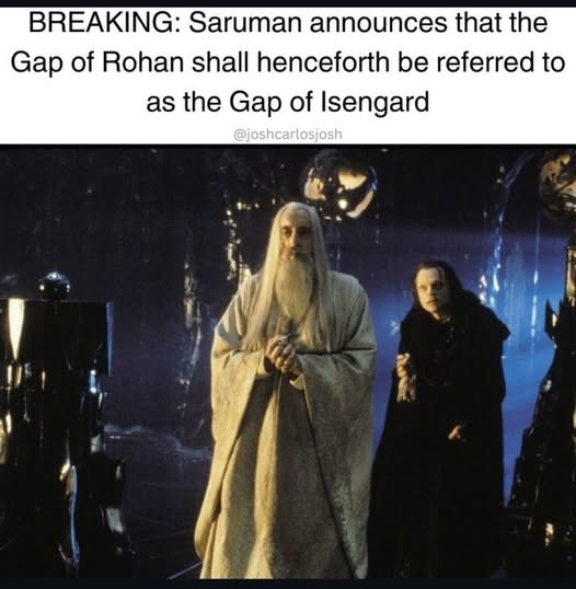 A still image from The Lord of the Rings shows Saruman the White, in his white robes, standing beside a dark-robed figure…