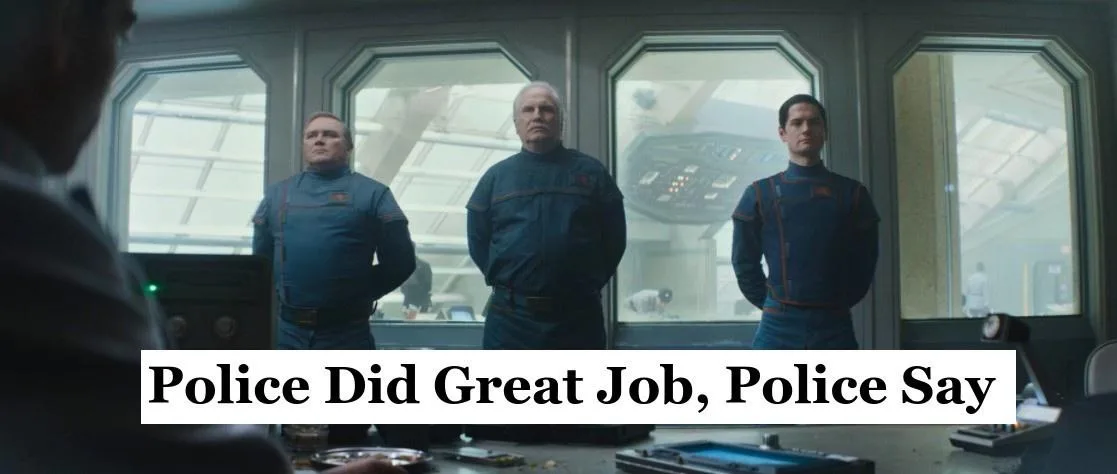 Three men in blue uniforms stand stiffly in a spaceship control room, looking serious as they face someone off-camera. A…