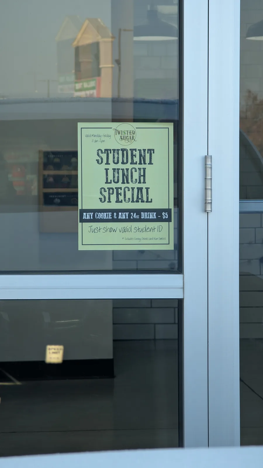 A light green promotional poster for 'Twisted Sugar' is taped to a glass door, advertising a 'Student Lunch Special'…