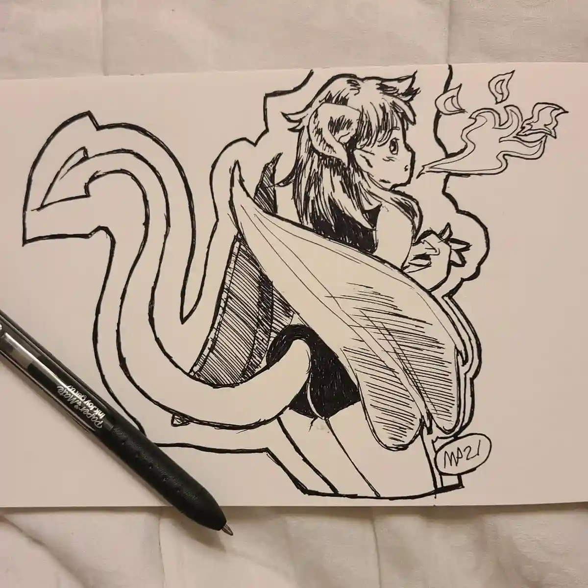 A black-and-white ink drawing on paper shows an anime-style character with large wings, a long tail, and pointed ears…