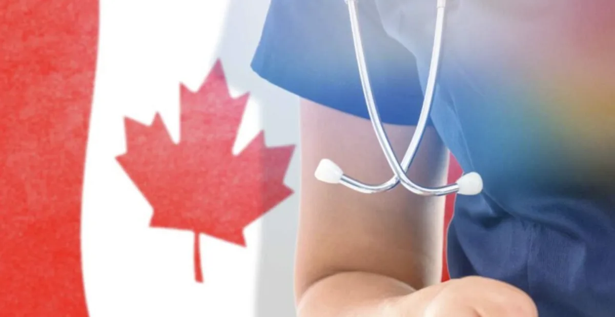 A person in blue medical scrubs with a stethoscope around their neck is shown against a blurred Canadian flag background…