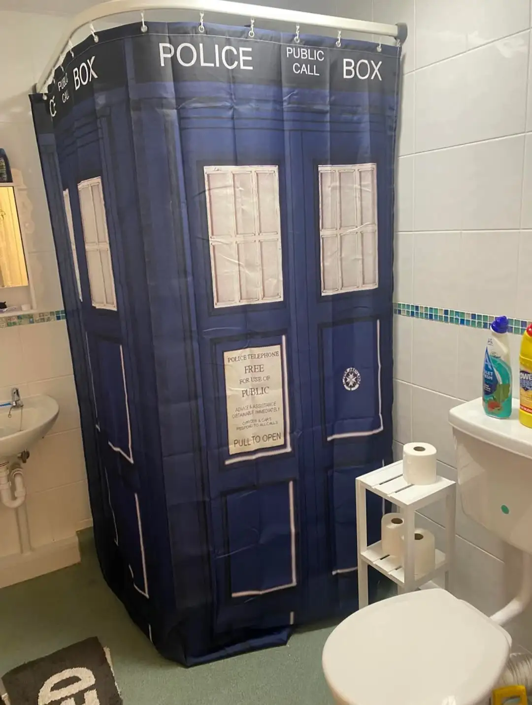 A bathroom features a shower curtain printed to look like a blue British police box, complete with 'POLICE PUBLIC CALL BOX'…