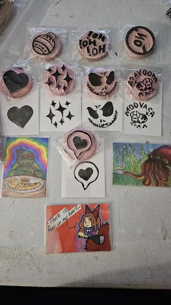 A collection of handmade clay stamps and their corresponding stencil designs are laid out on a surface. The stamps, mostly…