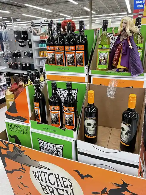 A store display of Halloween-themed wine bottles labeled 'Witches Brew' and 'St. Julian Head Games' with skull labels…