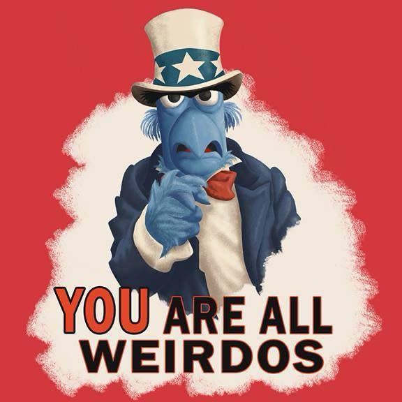 A blue Muppet character wearing a top hat with a star and a suit, pointing accusingly at the viewer against a red…