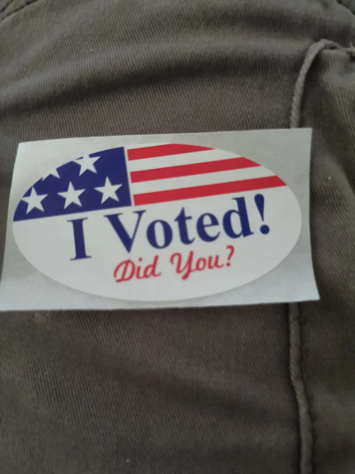 A close-up photo shows an oval 'I Voted! Did You?' sticker with a partial American flag design (blue canton with white stars…
