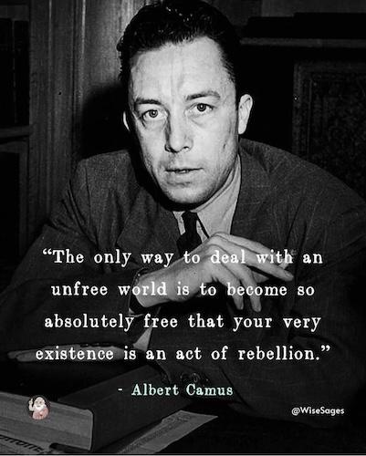 A black-and-white photo of Albert Camus looking directly at the camera with a serious expression, his hand resting near his…