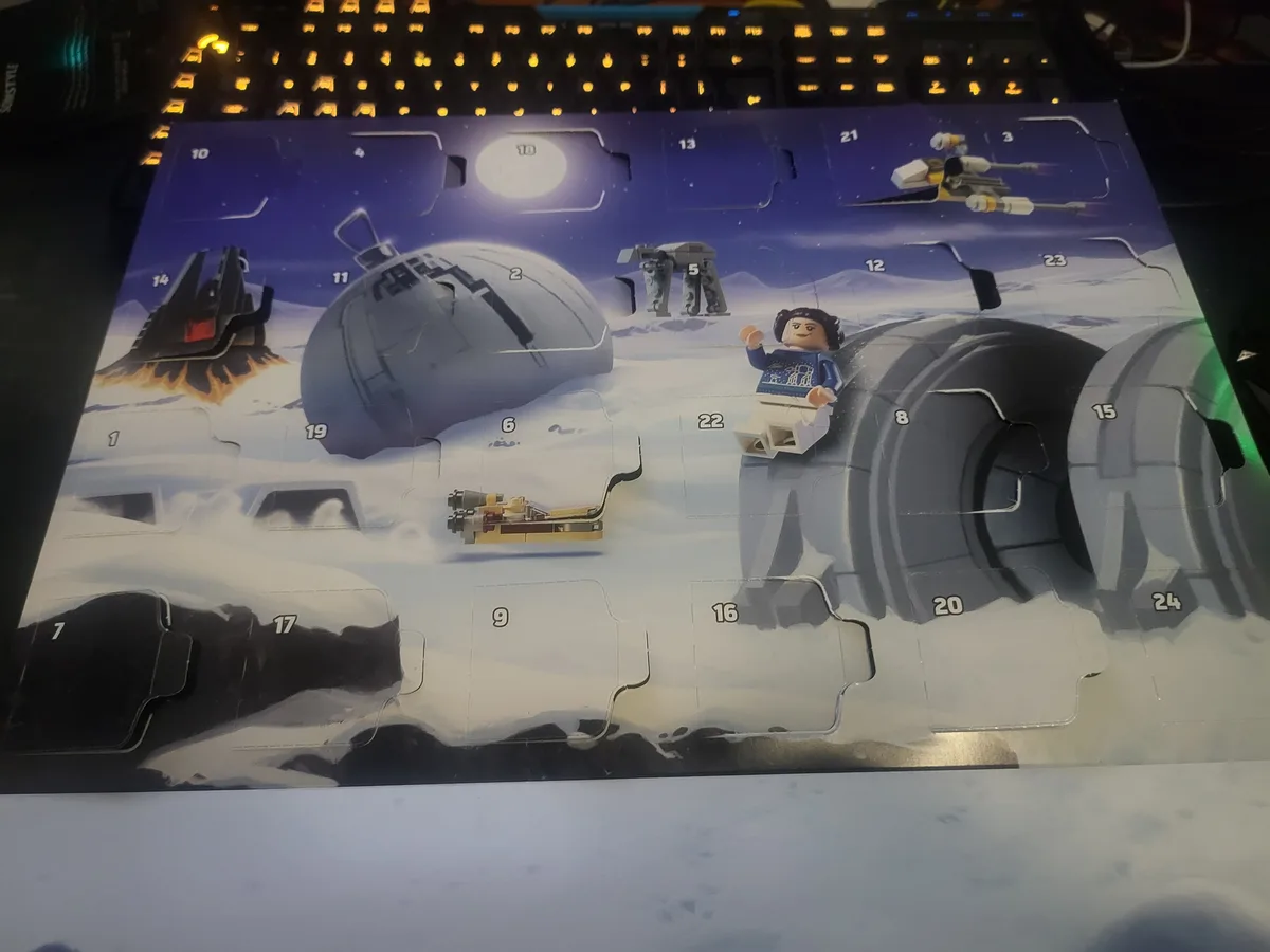 A Lego Star Wars Advent calendar is shown with many numbered compartments open, revealing Star Wars-themed miniatures like a…
