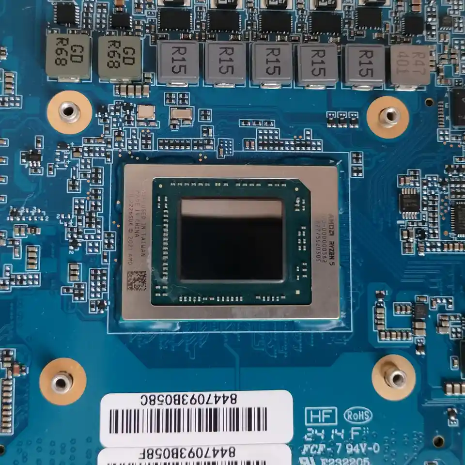 A close-up photo of a blue computer motherboard showing an AMD Ryzen 5 CPU socket with visible text on the chip and…