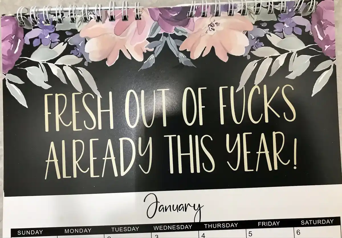 A close-up of a spiral-bound calendar with a floral design at the top, showing the month of January. The calendar page has…