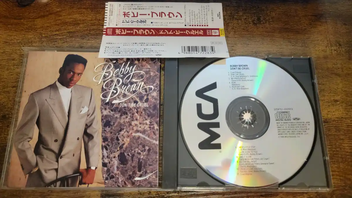 A physical copy of Bobby Brown's 1988 album 'Don't Be Cruel' is shown open, revealing the CD inside its case. The album…