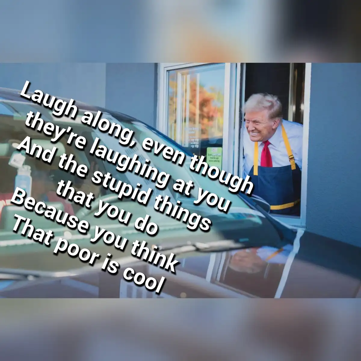A man with white hair, wearing a white shirt, red tie, and blue apron with yellow straps, leans out of a drive-thru window…