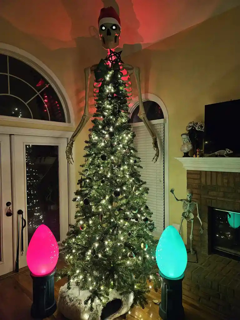 A large skeleton wearing a red and white Santa hat with glowing eyes stands behind a decorated Christmas tree, its ribcage…