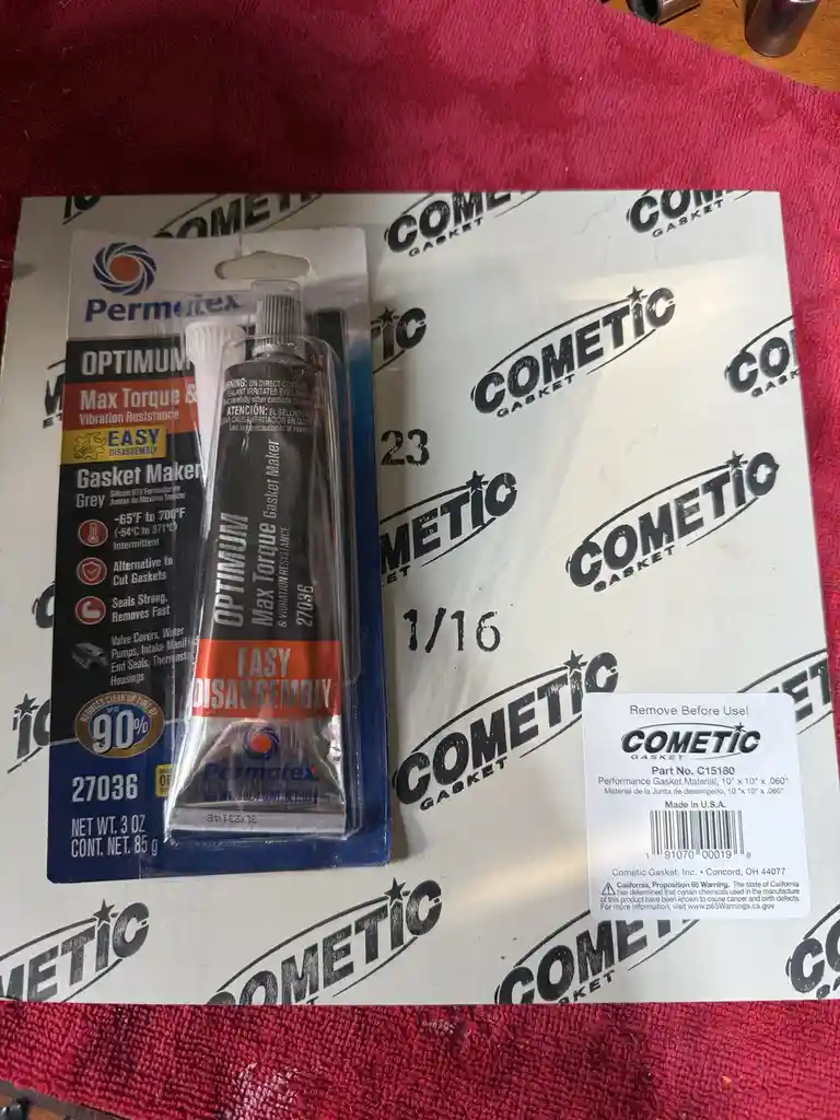 A close-up photo shows a tube of Permatex Optimum Max Torque Gasket Maker in its packaging, placed on a sheet of Cometic…