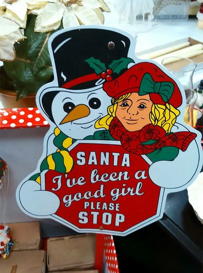 A festive Christmas sign features a cartoon snowman and a smiling girl in holiday attire holding a red stop sign. The sign…