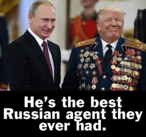 Two men stand side by side; the man on the left wears a dark suit and tie, while the man on the right wears a decorated…