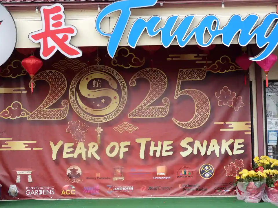 A festive red banner for the 2025 Year of the Snake features a golden snake design within the number 2025, Chinese…