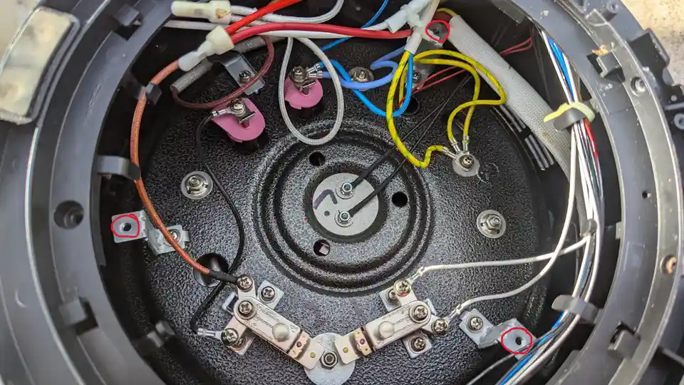 A close-up photo of the internal wiring and components of an appliance, likely a speaker or subwoofer, showing various…