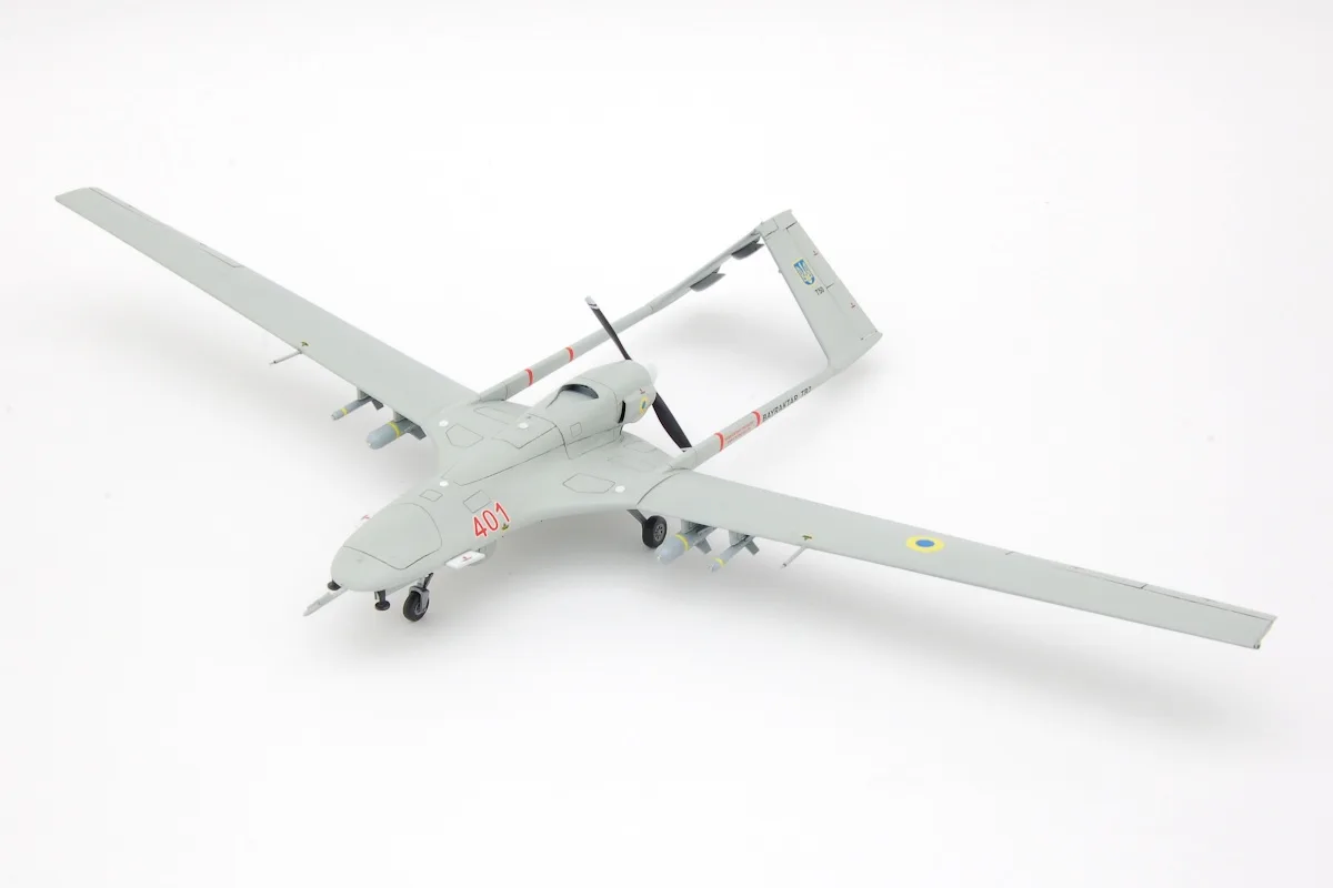 A gray model of a small unmanned aerial vehicle (UAV) with a propeller, landing gear, and markings including the number…