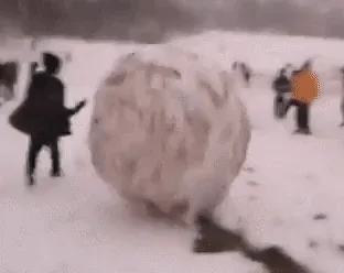 A sequence of six blurry, snowy images shows a massive snowball rolling through a park as people chase and try to stop it…