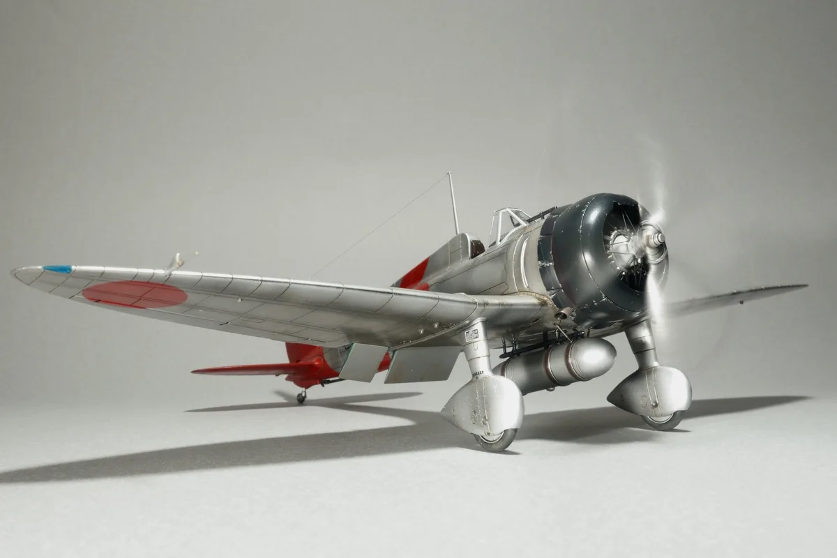 A highly detailed scale model of a silver and red Japanese World War II fighter plane, likely a Nakadžima Sakae-powered…