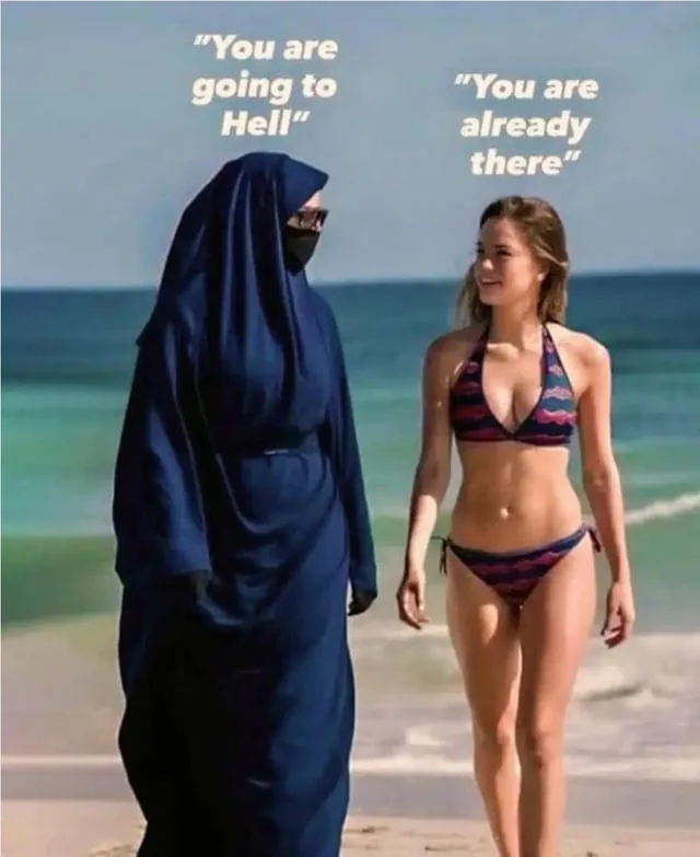Two women stand on a beach; one is fully covered in a dark blue burqa with sunglasses, the other is in a revealing bikini…