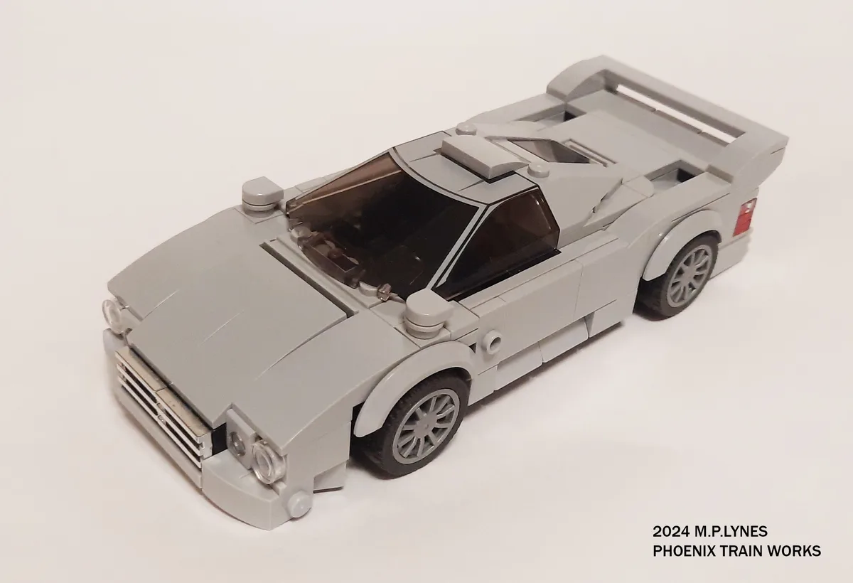 A gray Lego model of a futuristic-looking sports car with a large rear wing, transparent windows, and detailed wheels…