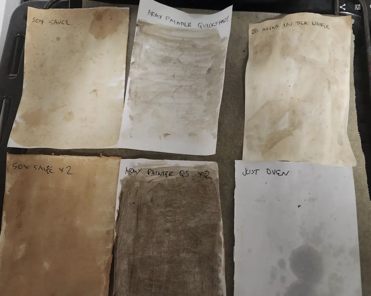 Six pieces of paper arranged on a baking tray, each stained with different methods to simulate aged paper. Handwritten…