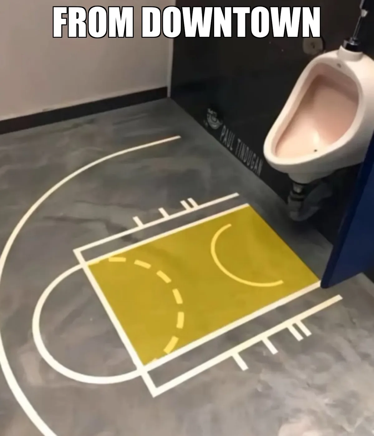 A bathroom floor features a painted basketball court with a yellow key area and white lines, positioned next to a white…