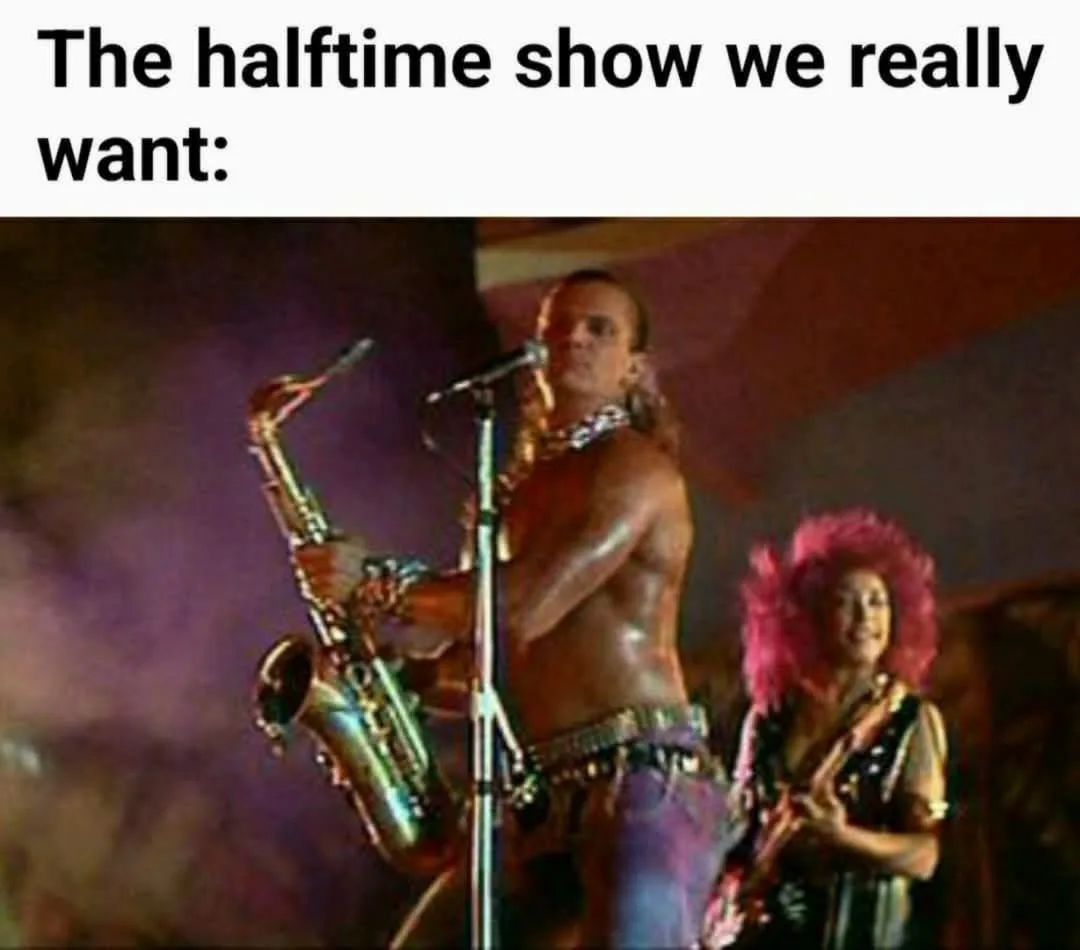A shirtless man with long hair plays a saxophone on stage while a woman with a bright pink wig smiles beside him. The text…