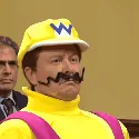 A six-panel image sequence shows a man in a yellow racing uniform with a 'W' on his helmet and a cartoon mustache…