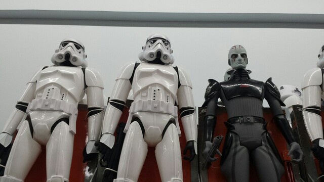 A row of Star Wars action figures, mostly white-armored Stormtroopers, with one black-armored figure standing out among…