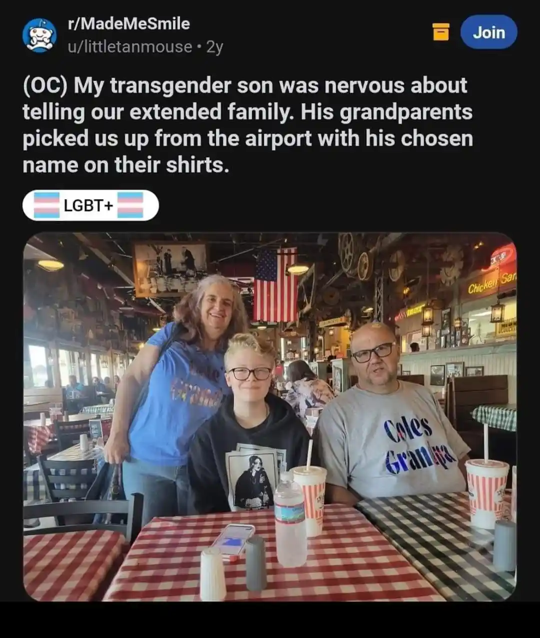 A family photo shows a young person with glasses sitting at a red-and-white checkered table in a restaurant, flanked by two…