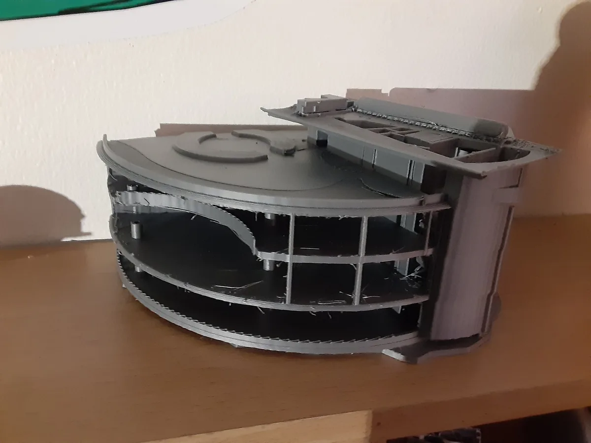A 3d printed model of a CD player is shown, but it's hollow and lacks internal components, sitting on a wooden shelf. The…