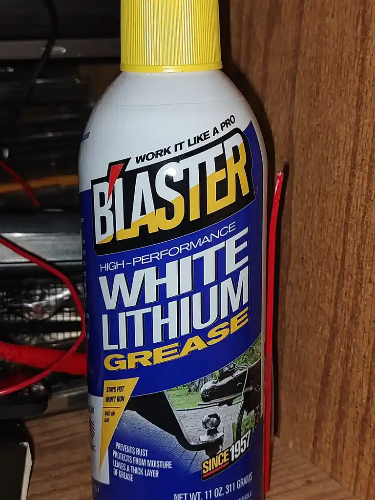 A close-up photo of a white aerosol can with a yellow cap, labeled 'BLASTER HIGH-PERFORMANCE WHITE LITHIUM GREASE'. The…